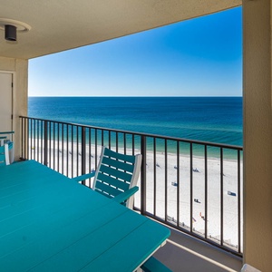 A turquoise table and chairs on the balcony offer a perfect spot to enjoy the breathtaking beachfront view