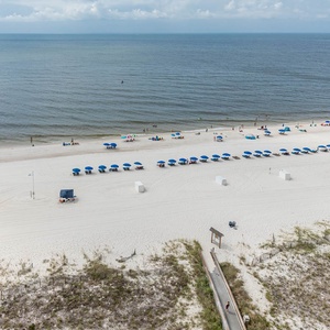 Balcony veiw of the serene beachfront with white sand, colorful umbrellas, and guests enjoying the tranquil shoreline
