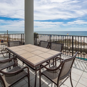 The balcony area features a tiled table and chairs, loungers, and a second floor beachfront view over the pool area