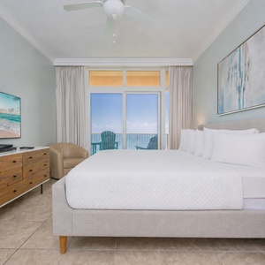 Experience restful nights in this master bedroom with a large king bed, TV, and a view of the tranquil waters beyond