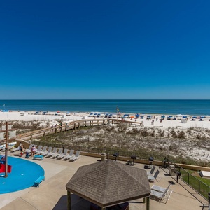 The vibrant pool area features a playful pirate ship splash park and a view of the beach and colorful umbrellas
