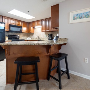 Granite countertops complement the warm wood cabinetry in this inviting kitchen area with a breakfast bar and seating