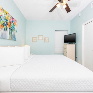Serene blue walls in this inviting master suite bedroom with a comfortable king bed, adjoining bath, and TV