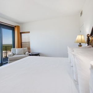 Comfortable master bedroom featuring a king bed, cozy seating area, and beautiful views from large sliding glass doors