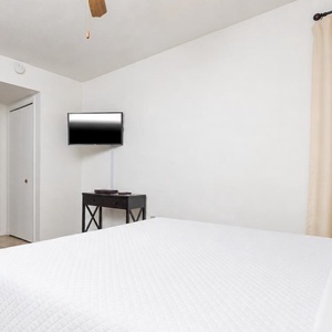 This cozy bedroom features a comfortable bed, a TV for entertainment, and elegant wooden cabinetry for storage