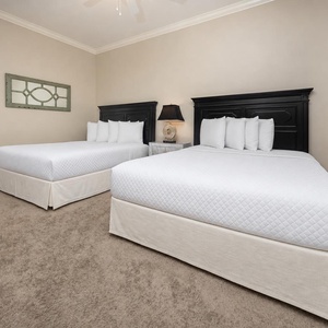This bedroom features two comfortable queen beds, stylish black furniture, and colorful artwork for a cheerful atmosphere