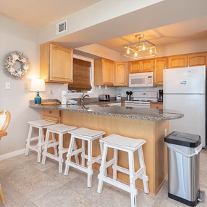 This kitchen features granite countertops, light wood cabinetry, and a cozy dining area, perfect for enjoying meals together