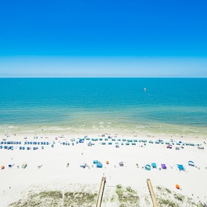 Gaze at the vibrant beach scene with colorful umbrellas and people enjoying the sun along the shoreline