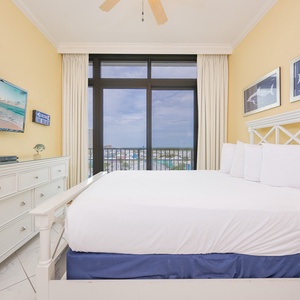 Cheerful guest bedroom featuring a plush queen bed and a large window with a scenic view of the vibrant surroundings