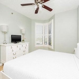 This guest serene bedroom features a comfortable bed, a TV, and a charming bay window that invites natural light