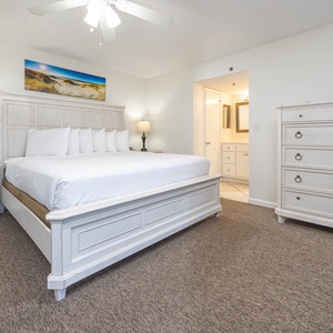 Master bedroom featuring a plush king bed, stylish decor, and a serene beach-themed artwork above