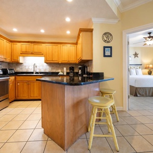 Warm wooden cabinetry complements the modern kitchen with a breakfast bar and coffee station