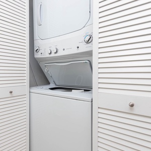 This laundry area features a stacked washer and dryer behind sleek white cabinetry for convenient in-unit laundry