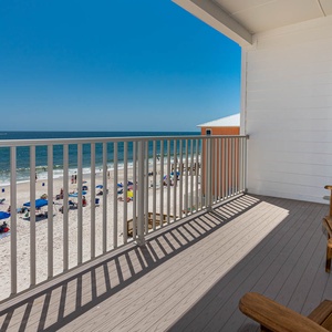 This balcony offers a stunning beachfront view, complete with two wooden chairs for relaxing by the sea