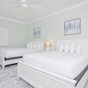 Serene guest bedroom featuring two queen beds, soft pillows, and coastal art that enhances the tranquil vibe