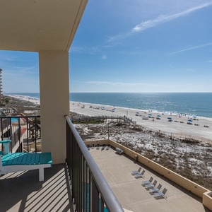 Relax on the private balcony with turquoise chairs, overlooking the serene beach and sparkling waters