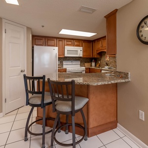 Warm wood cabinetry complements the granite countertops in this inviting kitchen area with a breakfast bar and seating
