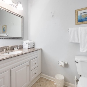 Bright guest bathroom featuring a granite countertop, large mirror, and neatly arranged towels for a refreshing experience