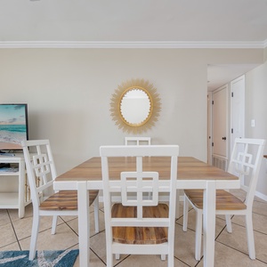 The dining area invites you to gather around warm wood tones while enjoying a moview on the TV