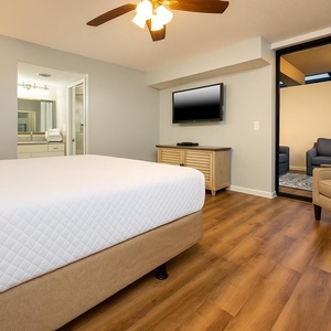 Cozy master bedroom featuring a king bed, mounted TV, and access to a private ground floor outdoor patio