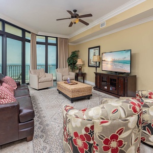 Living room featuring a cozy leather sofa with queen sleeper, floral chairs, and large windows showcasing beautiful views
