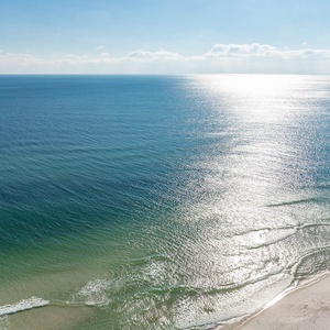 Experience tranquil waters glistening under the sun, inviting you to relax and enjoy the serene beach atmosphere