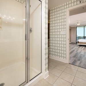 Refreshing master bathroom featuring a glass walk-in shower, elegant tile work, and a view into the master suite