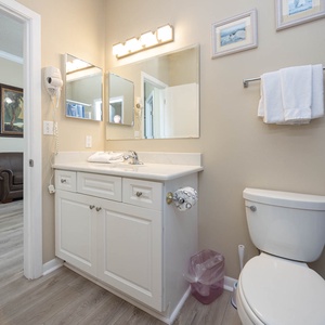 Bright bathroom featuring a white vanity, a spacious countertop, and a cozy view of the adjoining living area