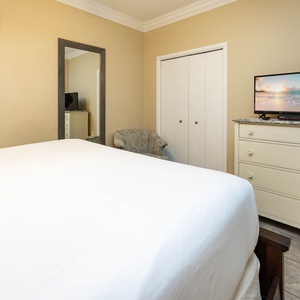 Guest bedroom features a plush king bed, a TV on a dresser, and a patterned accent wall, creating a welcoming retreat
