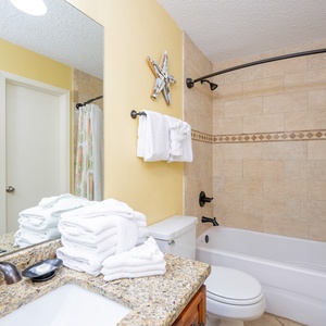 A bathroom features a granite countertop, modern fixtures, and neatly arranged towels for a refreshing experience