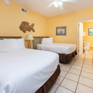 Rest comfortably in this cheerful guest room featuring two double beds, vibrant yellow walls, and charming coastal decor