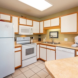 The fully-equipped kitchen features white appliances, light countertops, and ample cabinetry for a functional cooking space