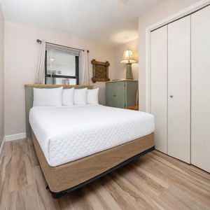 Guest room featuring a double bed with decorative pillows, a charming green cabinet, and natural light from the window
