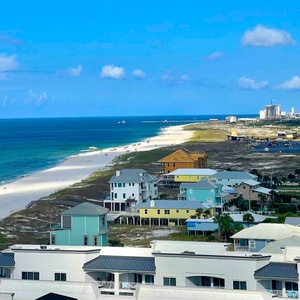 Marvel at the stunning shoreline, stilt homes below, and the distant pier stretching along the gulf coast