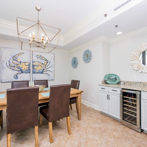 Gather around the wooden dining table, adorned with coastal art and complemented by stylish seating for memorable meals