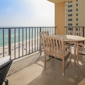 Enjoy dining on the spacious balcony with wooden furniture and a breathtaking view of the sandy beach and waves