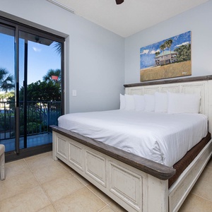 Serene guest bedroom with a comfortable king bed, stylish decor, and views of lush greenery from the balcony