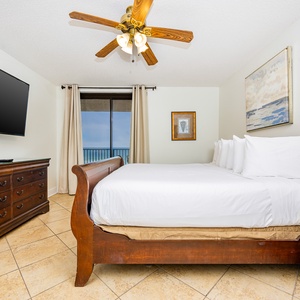 Rest in the spacious master bedroom with a large king bed, elegant furnishings, and a view of the beach from the balcony