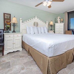 Master bedroom features a king bed with plush pillows, a stylish chair, and access to the gulf front balcony
