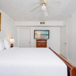 The master bedroom features a floral-patterned bedspread, a wall-mounted TV, and an adjoining bathroom for added convenience