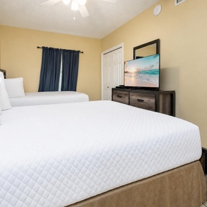 Rest in this inviting guest bedroom with two double beds, a TV for entertainment, and warm decor for a comfortable stay