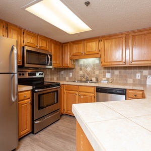 Rich wooden cabinetry and tile backsplash complement the stainless appliances in this inviting kitchen