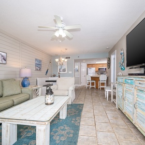 Living area features a green sofa, decorative accents, and a view toward the dining space and modern kitchen beyond