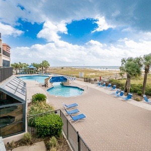 Relax by the pool area with lounge chairs, surrounded by palm trees and just steps away from the beach