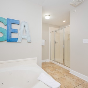 Relax in this inviting master bathroom featuring a jetted tub and a spacious walk-in shower, accented by coastal decor