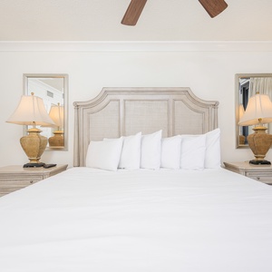 Elegant master bedroom featuring a plush king bed adorned with pillows, complemented by stylish lamps and mirrored accents