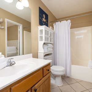 Bright bathroom featuring a spacious vanity, ample towels, and a relaxing tub-shower combination