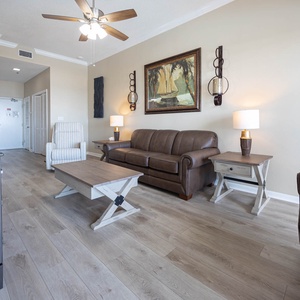 The living area features a brown leather sofa, a cozy armchair, and a rustic coffee table, creating a welcoming atmosphere