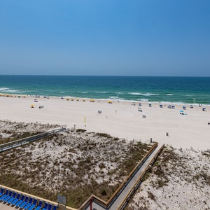 Beachfront view showcases soft white sand and tranquil turquoise waters under a bright blue sky