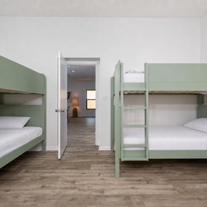 Guest room featuring two stylish green bunk beds, a king bed, and a cozy atmosphere, perfect for family getaways
